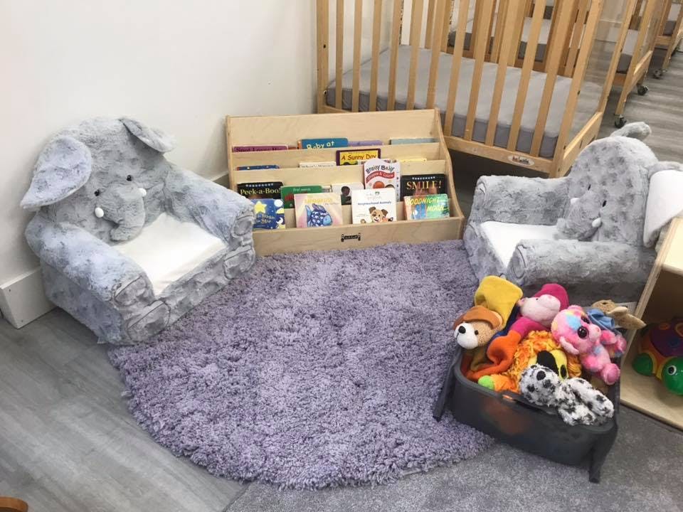 Two elephant-shaped chairs on a purple rug with a book display and toys