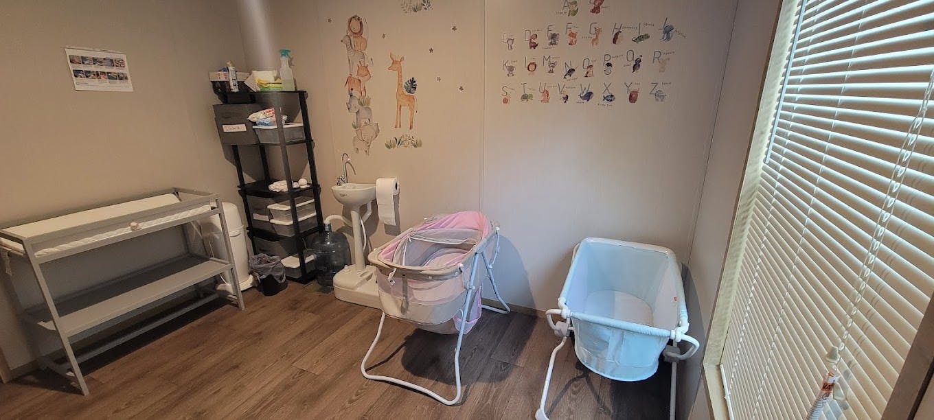 Changing table, storage shelf, and two baby bassinets in a room