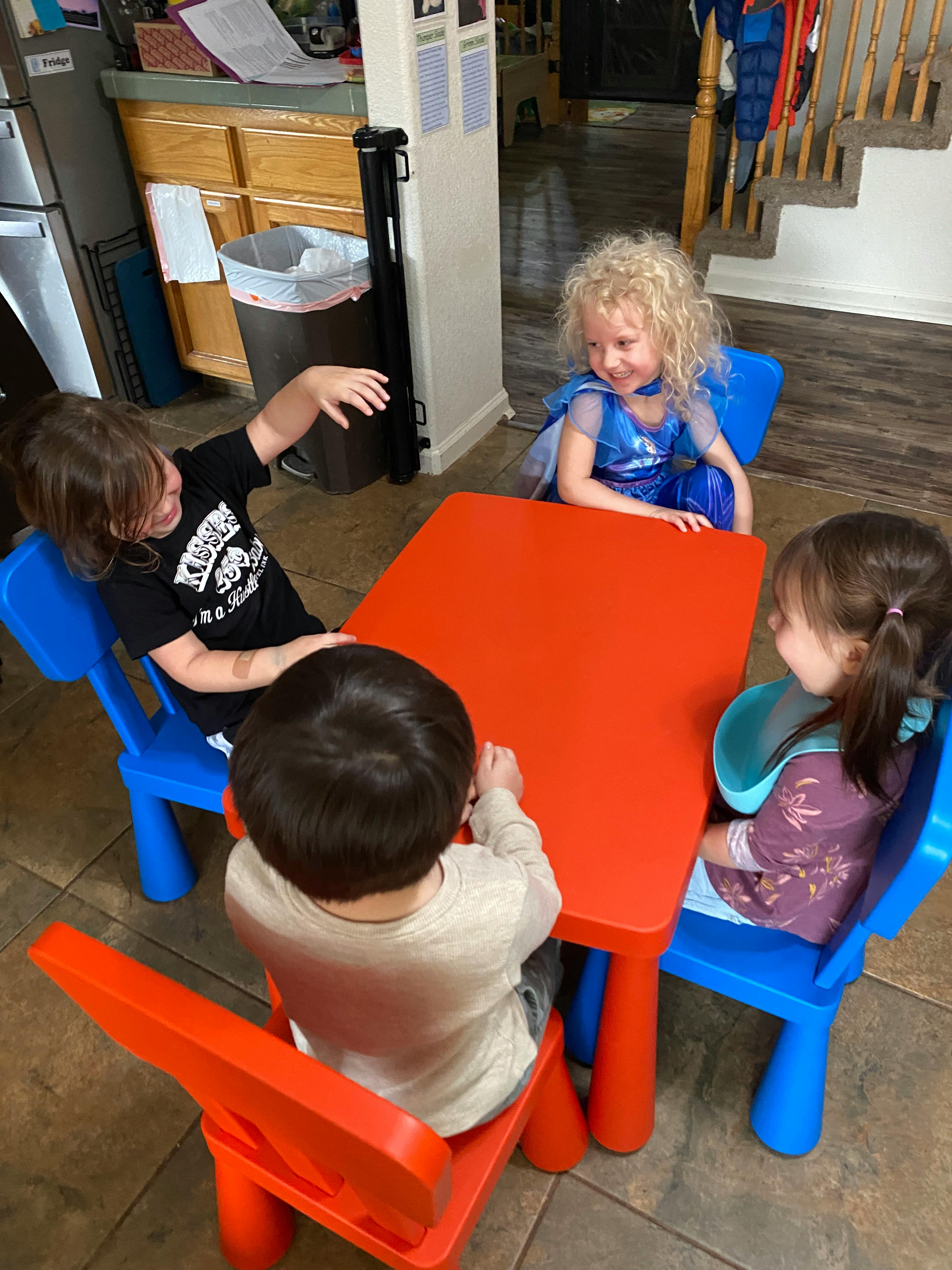 Four children sitting around a red table
