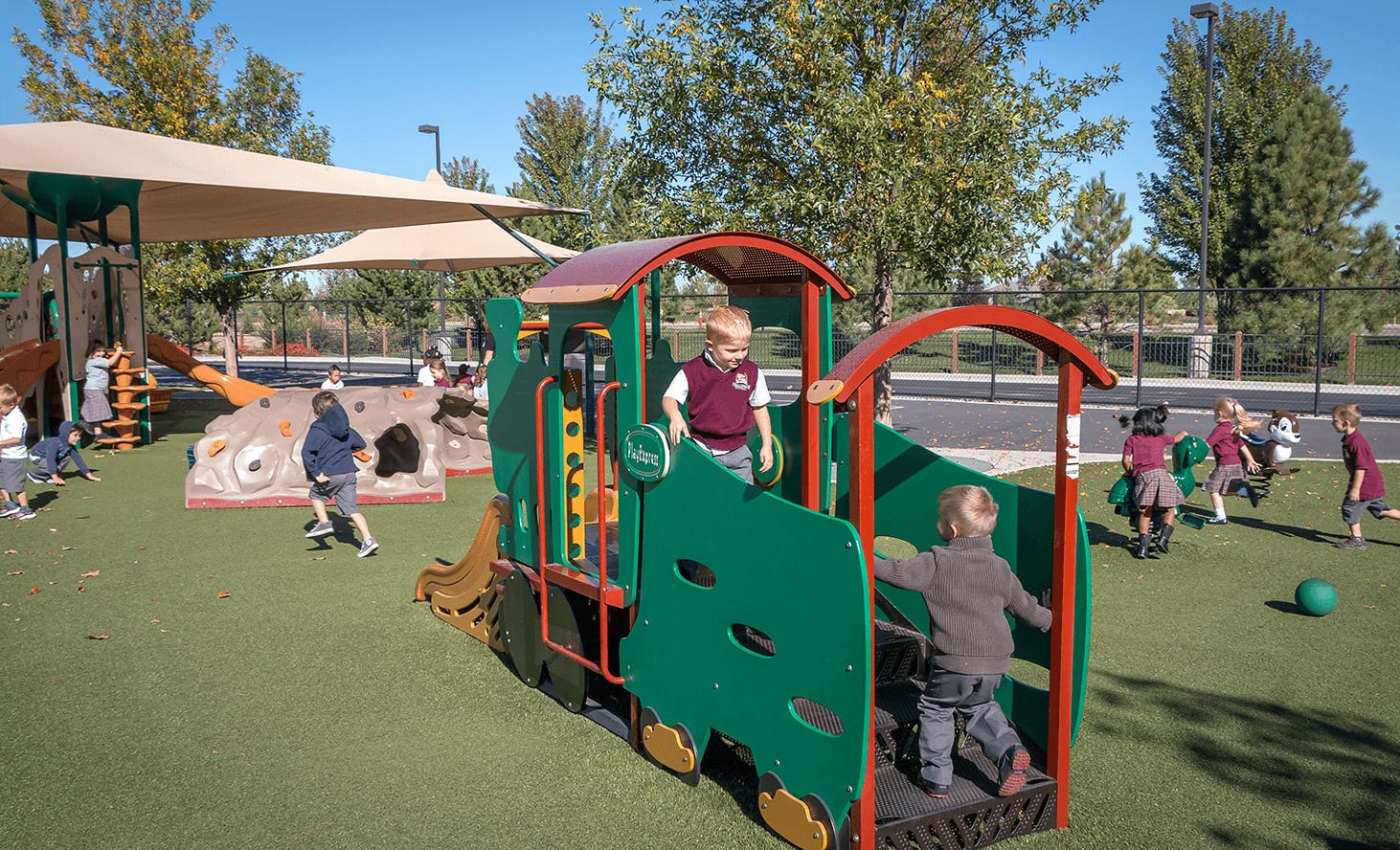 Children playing on a train structure and other playground equipment