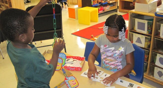 Child holding a chain of links, child at a table looking at cards