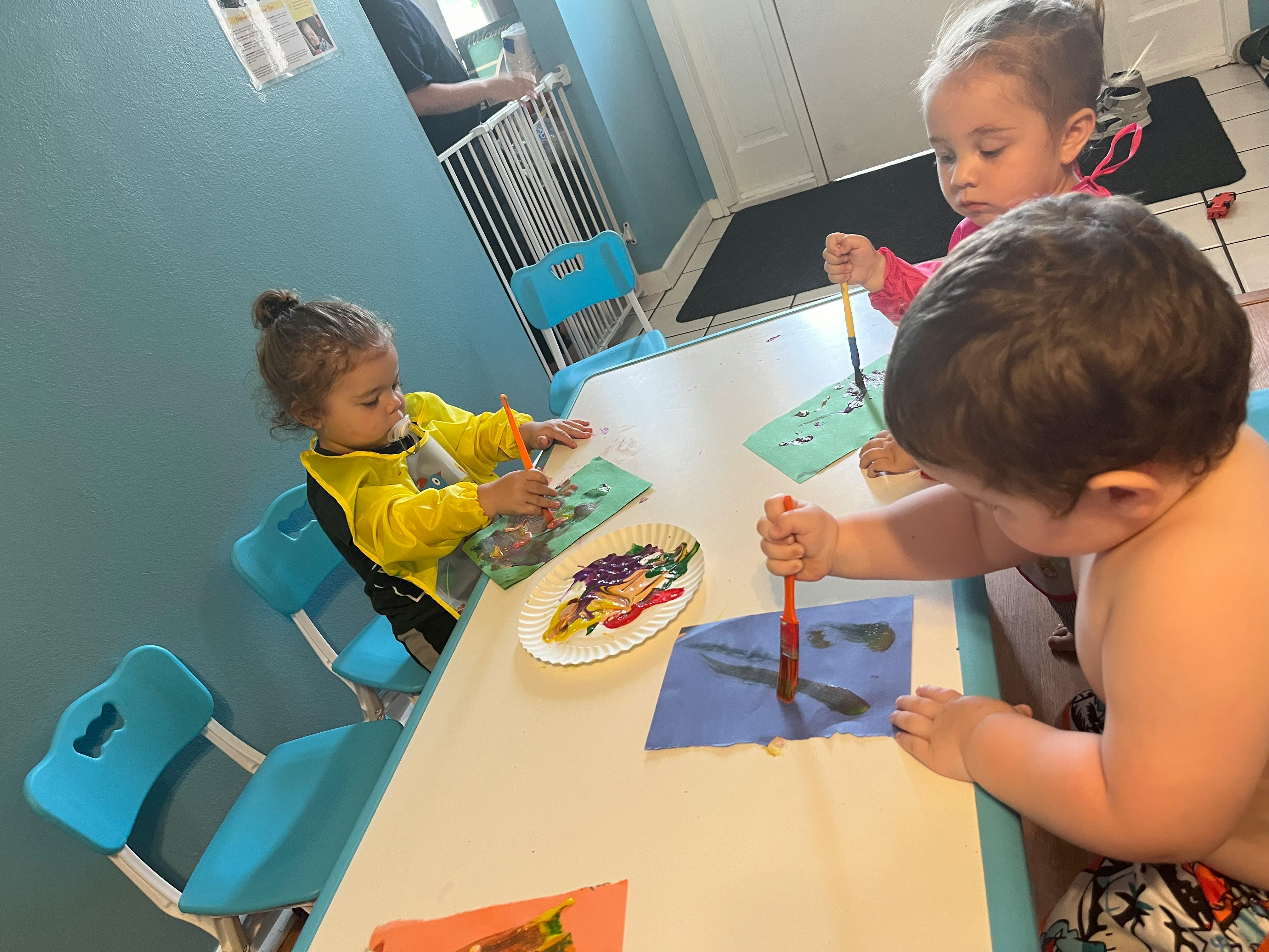Three children painting at a table
