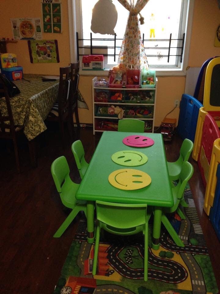 Green children's table with chairs and smiley face placemats in a classroom