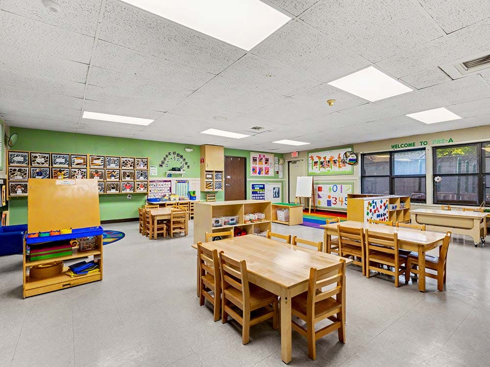 Empty classroom with small wooden tables and chairs