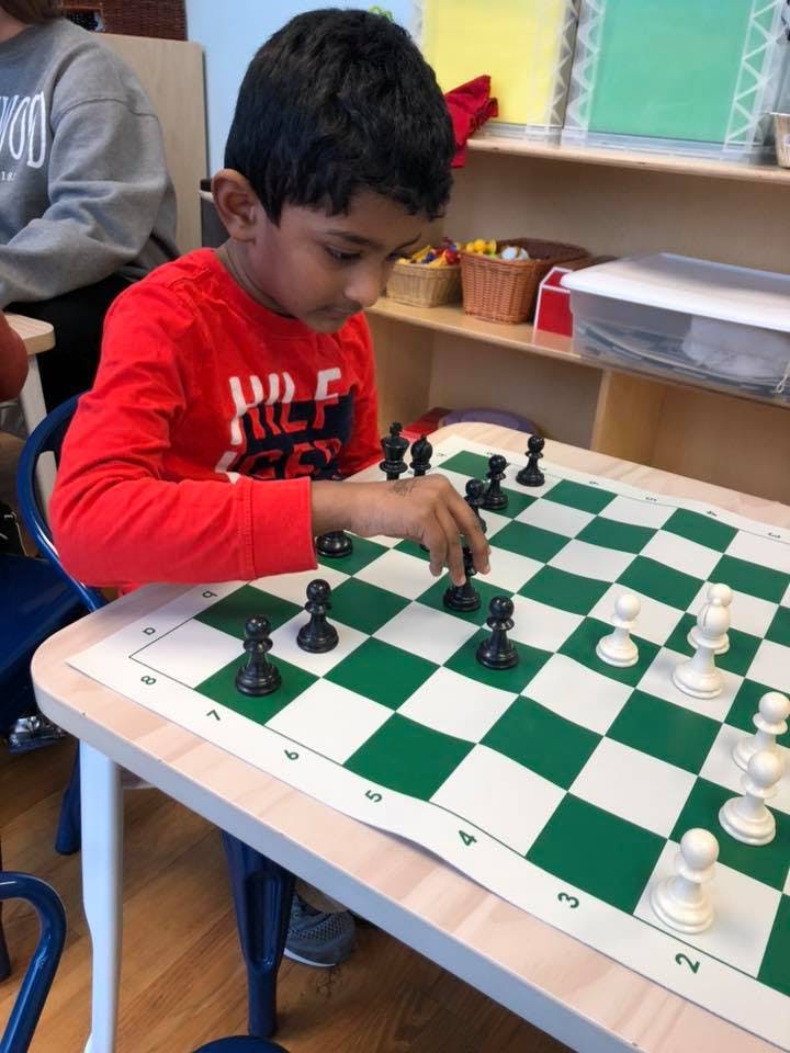 Child playing chess in a classroom