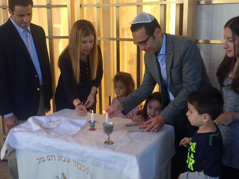 Adults and children lighting candles at a table