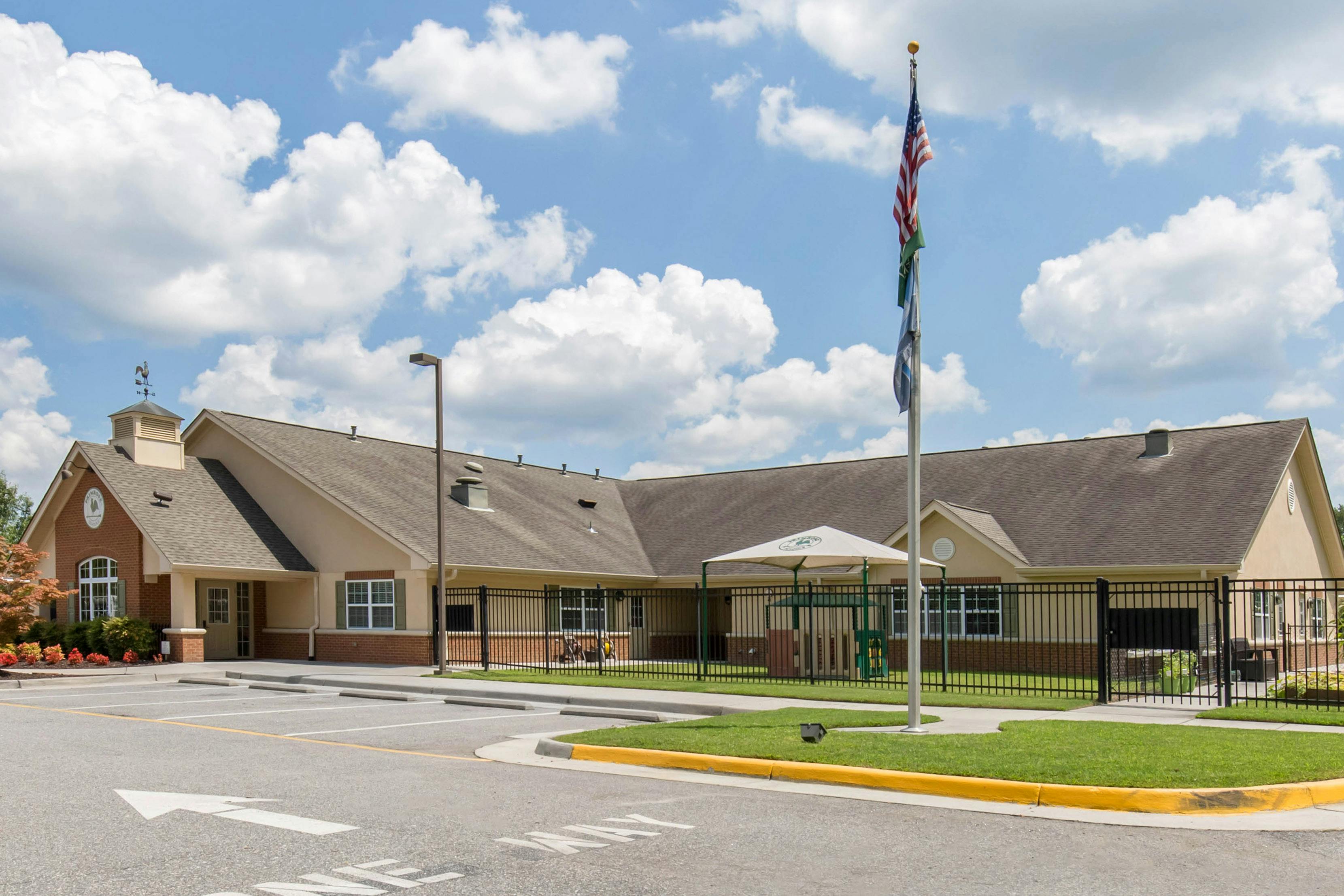 Single-story building with a cupola and weathervane, parking lot, and flagpole