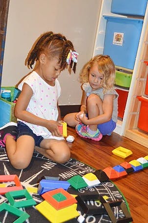 Two children playing with colorful blocks on the floor