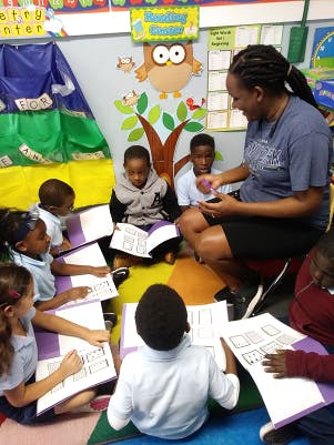 Adult and children sitting on floor in classroom with books