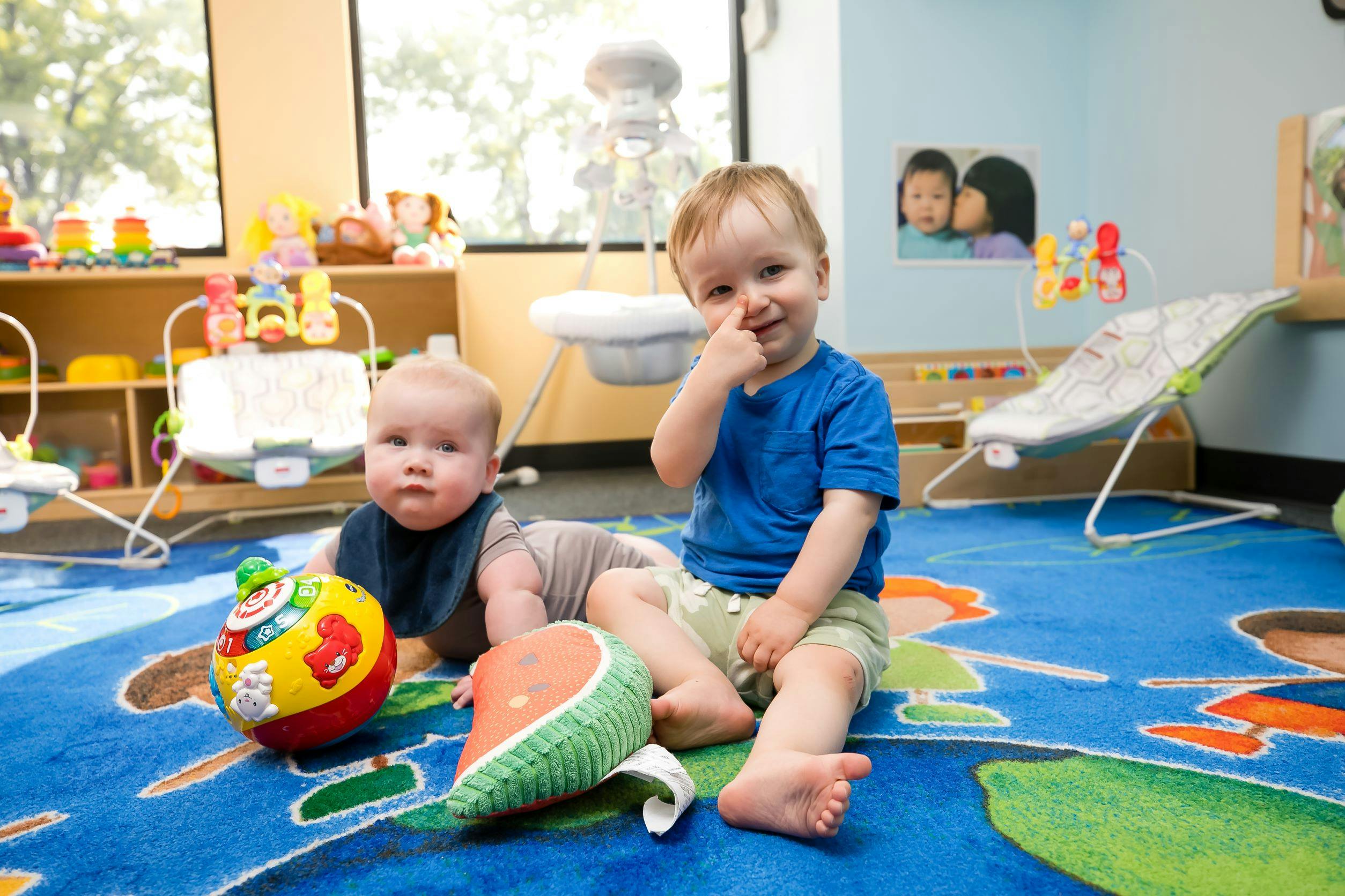 Two children playing with toys on a rug in a room