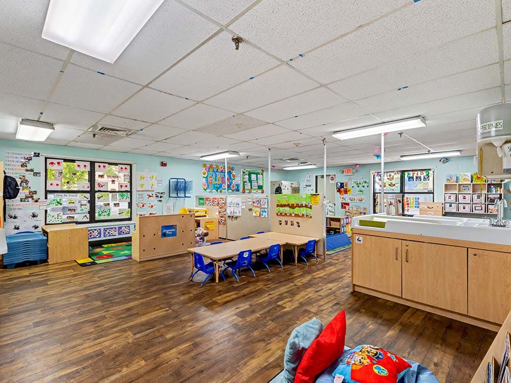 An empty daycare classroom with small tables and chairs