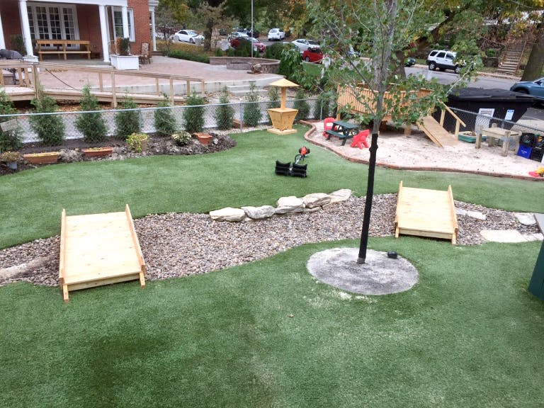 Backyard with artificial turf, gravel path, and wooden play structures