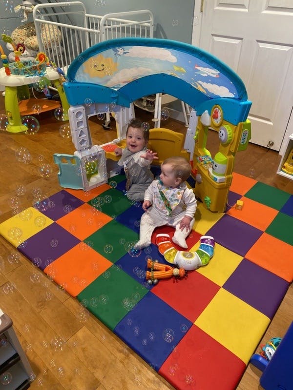 Two children playing on a colorful mat with toys