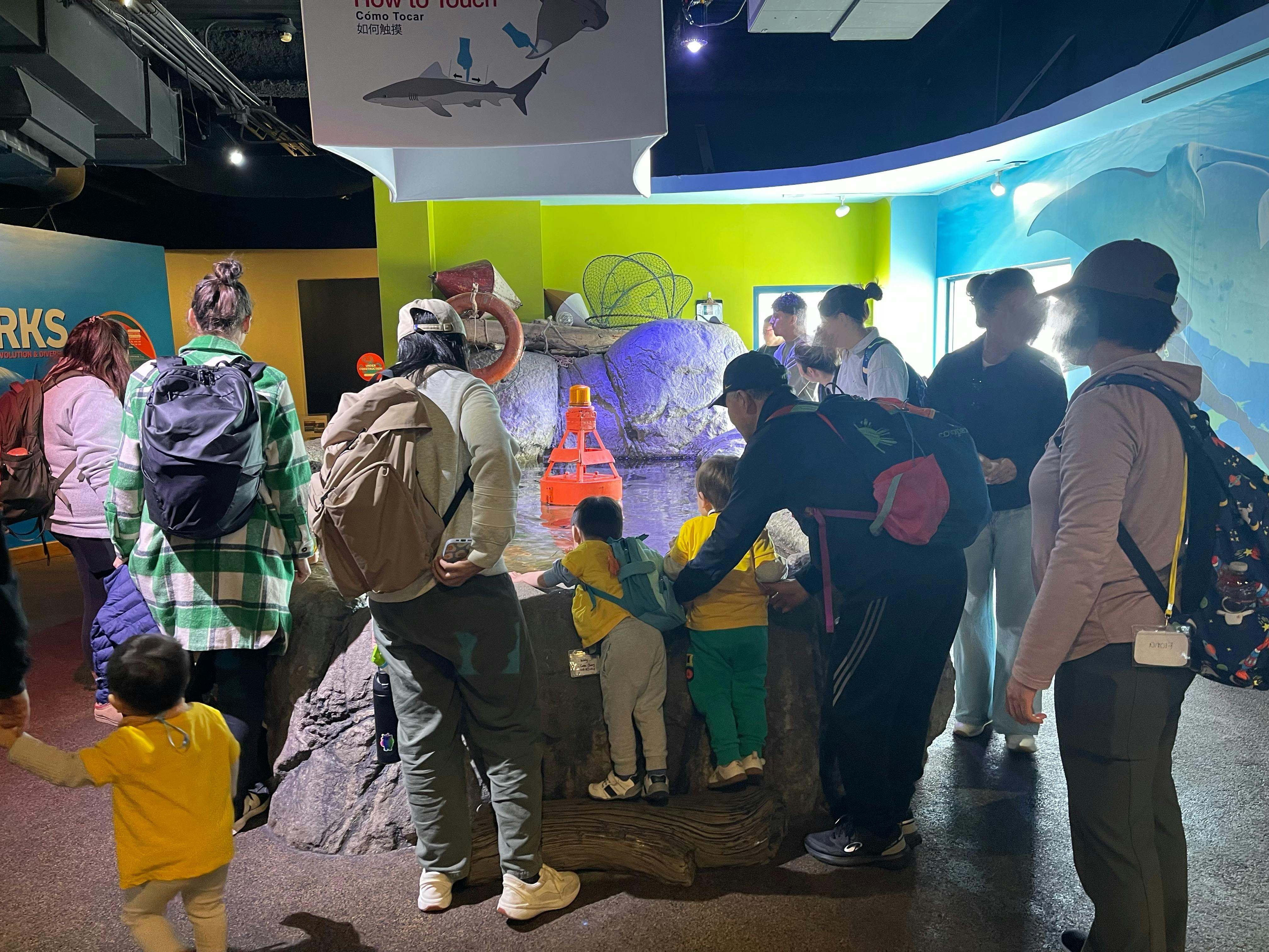 People and children at an exhibit with a buoy in water