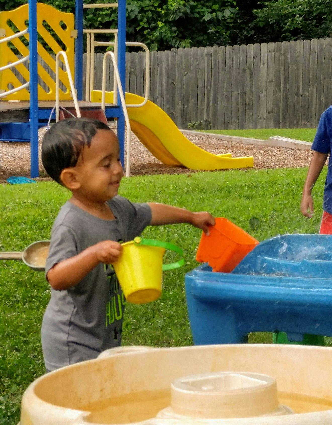 Child playing with buckets and water table on a playground