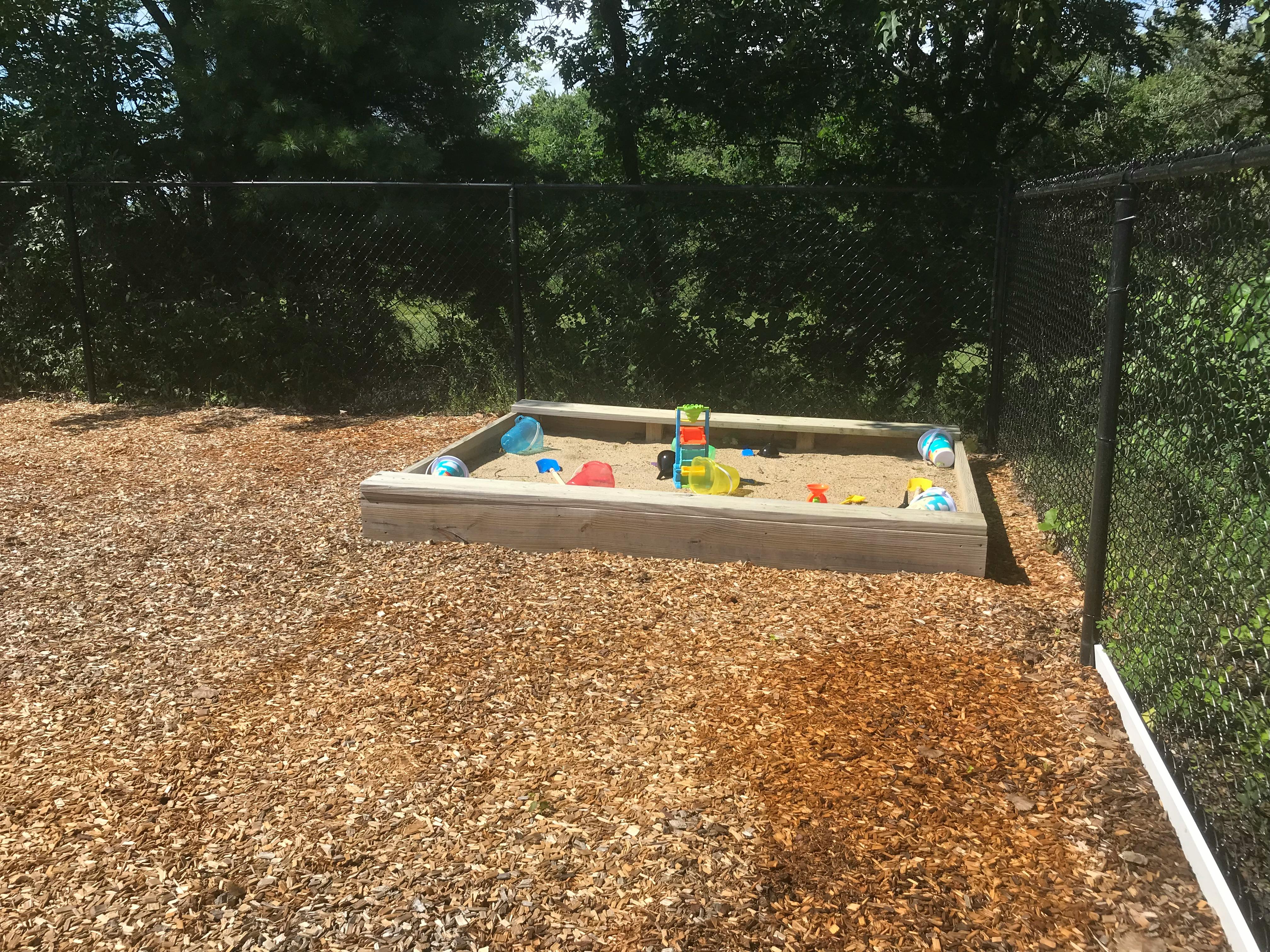 Sandbox with toys in a fenced area