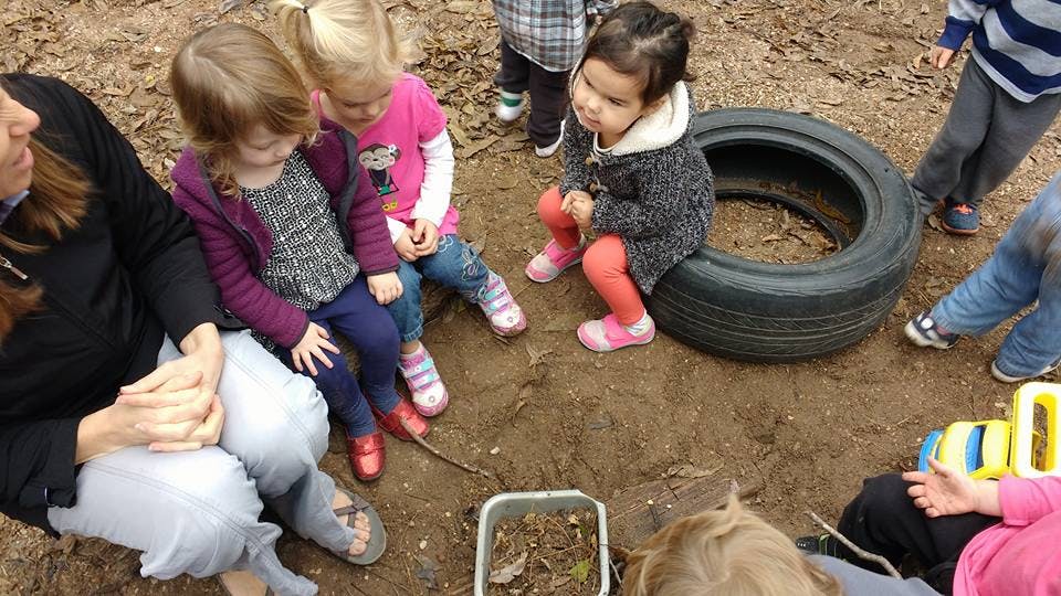 Adult and children sitting on the ground outdoors