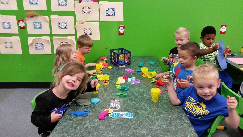Children playing with colorful toys at a table in a classroom
