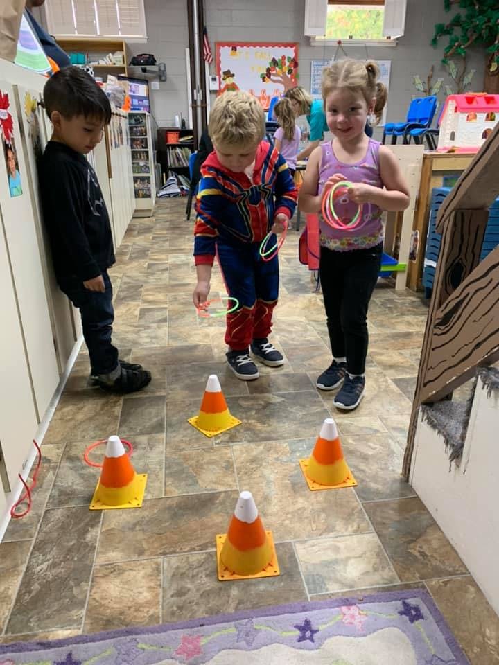 Three children playing a ring toss game with cones