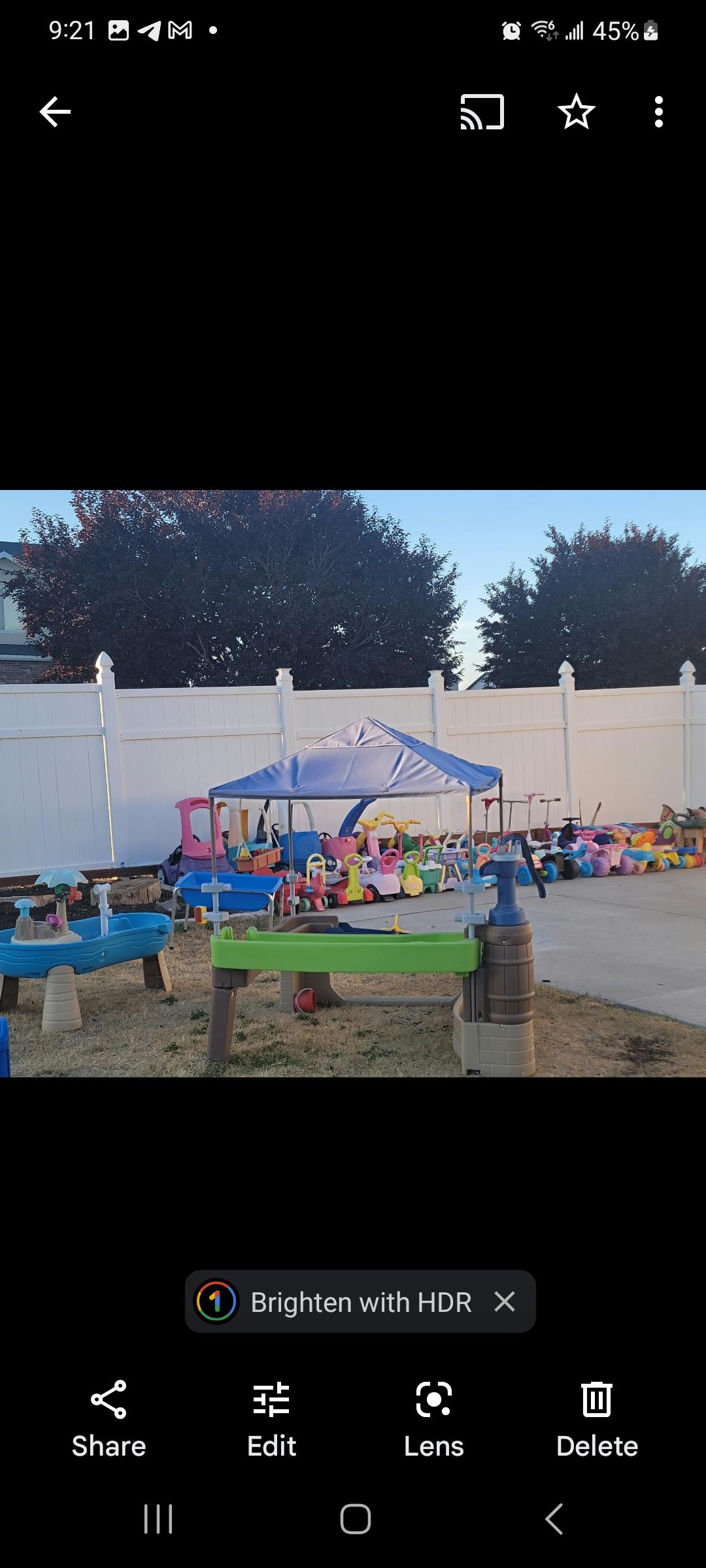 Outdoor play area with a blue canopy, water tables, and various toys
