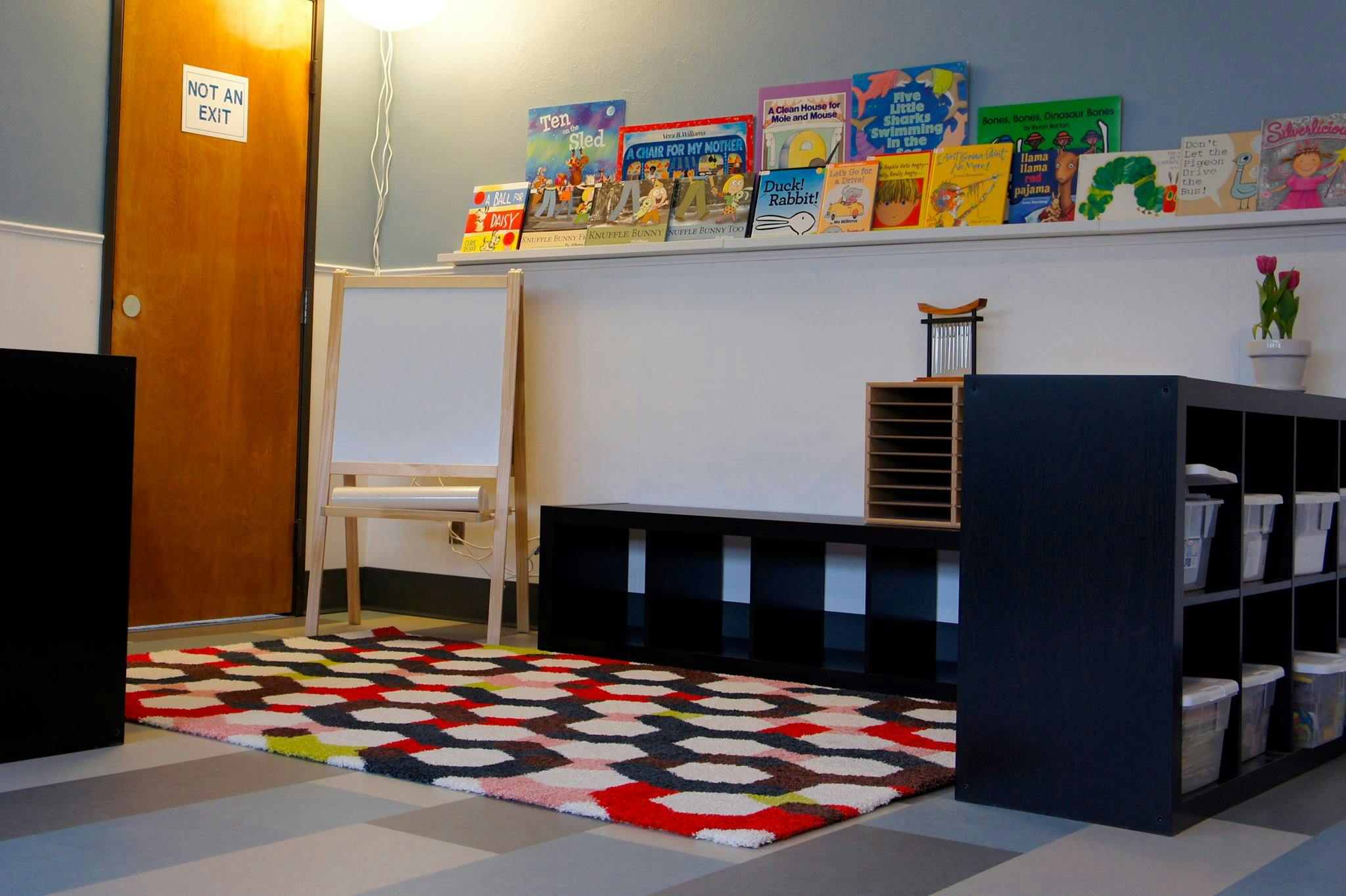 Classroom with books on a shelf, an easel, and storage units