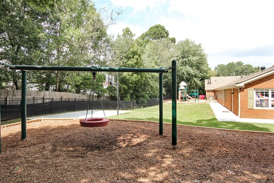 Tire swing on a playground with a building in the background