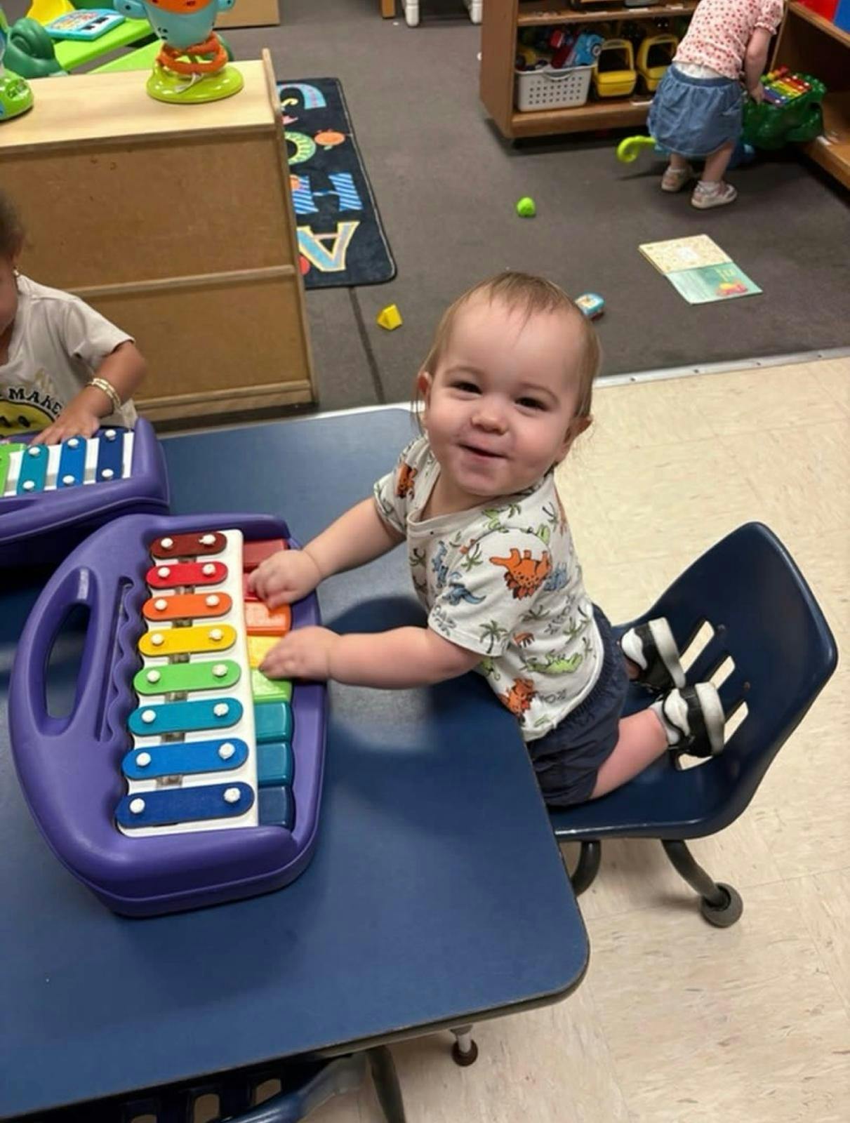 Child sitting at a table playing with a toy xylophone