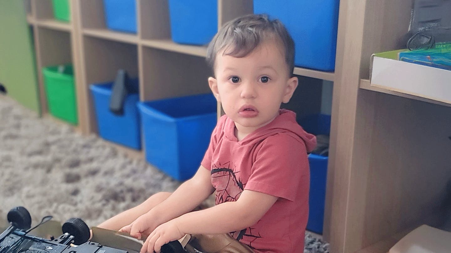 Child sitting on a rug in front of shelves with blue bins