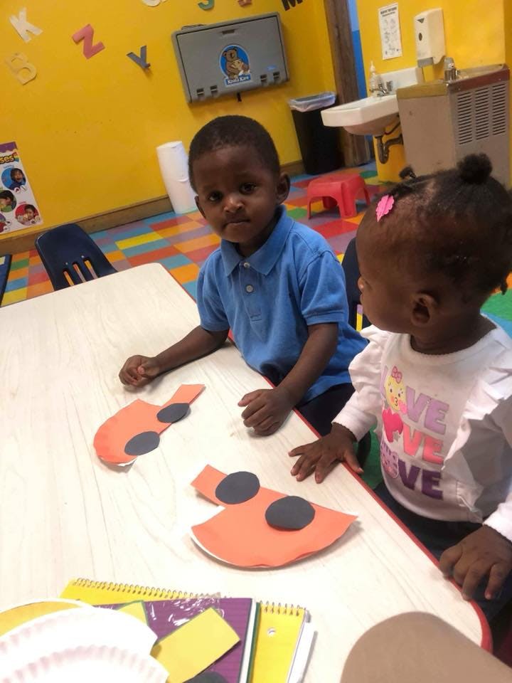 Two children at a table with craft cutouts