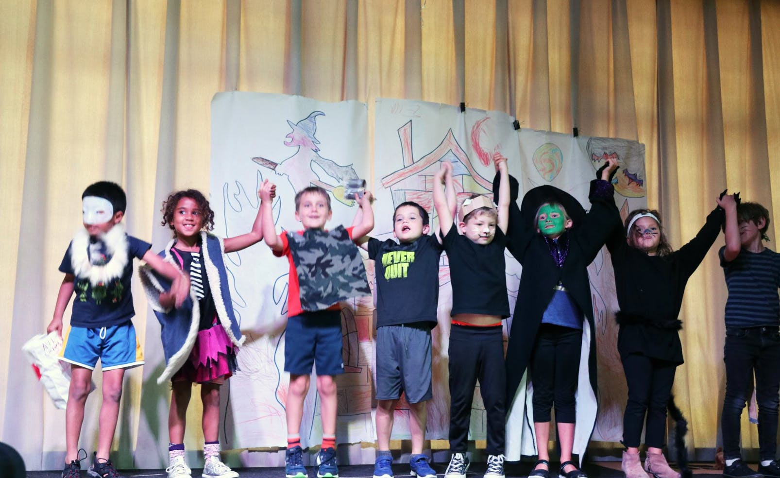 Children in costumes on a stage with arms raised