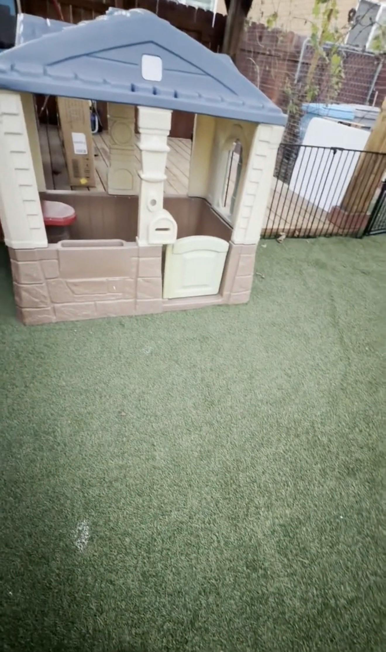Plastic playhouse on artificial grass in a backyard