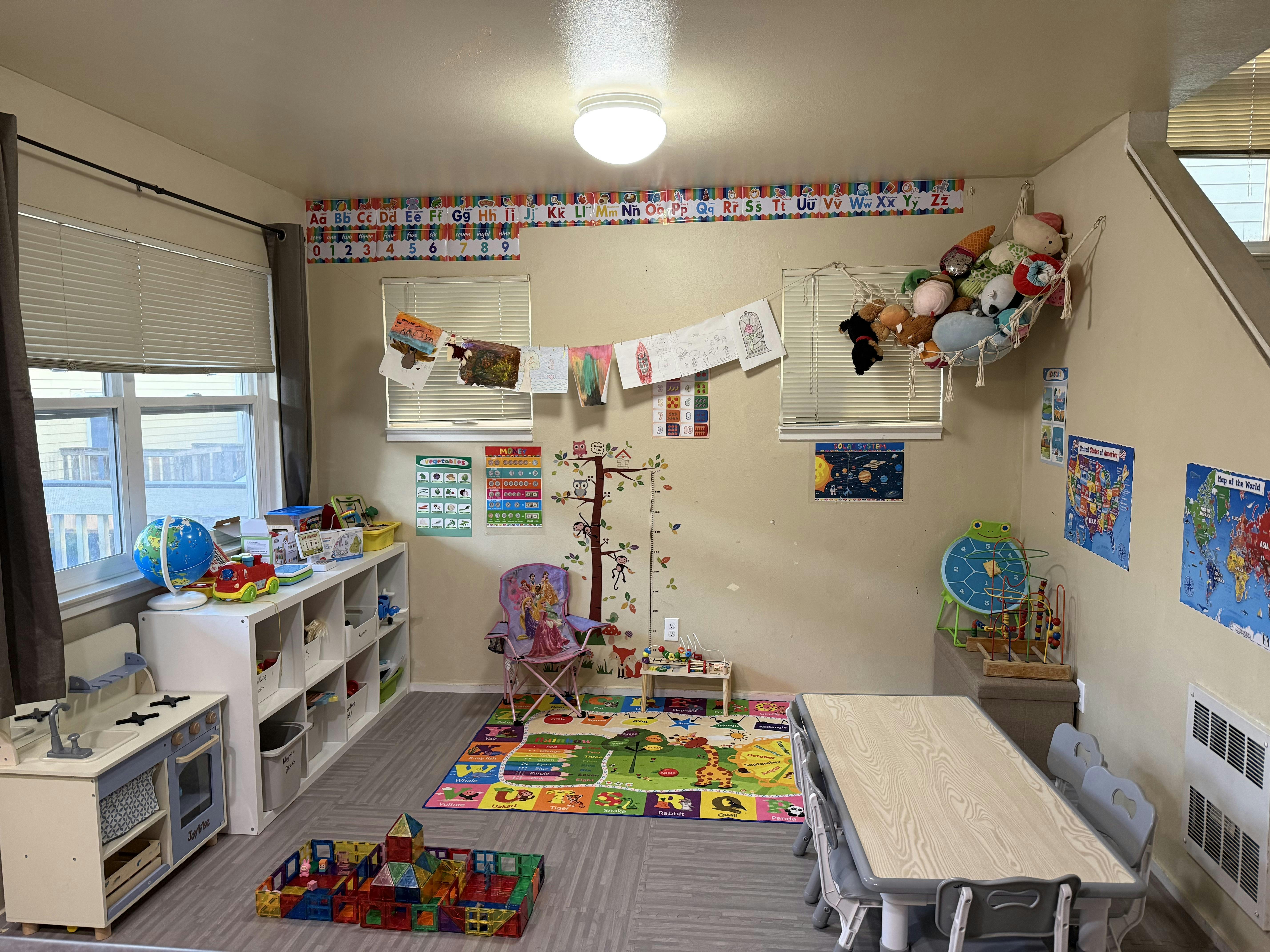 Child playroom with tables, chairs, toys, and educational wall posters