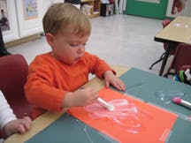 Child applying glue to paper in a classroom