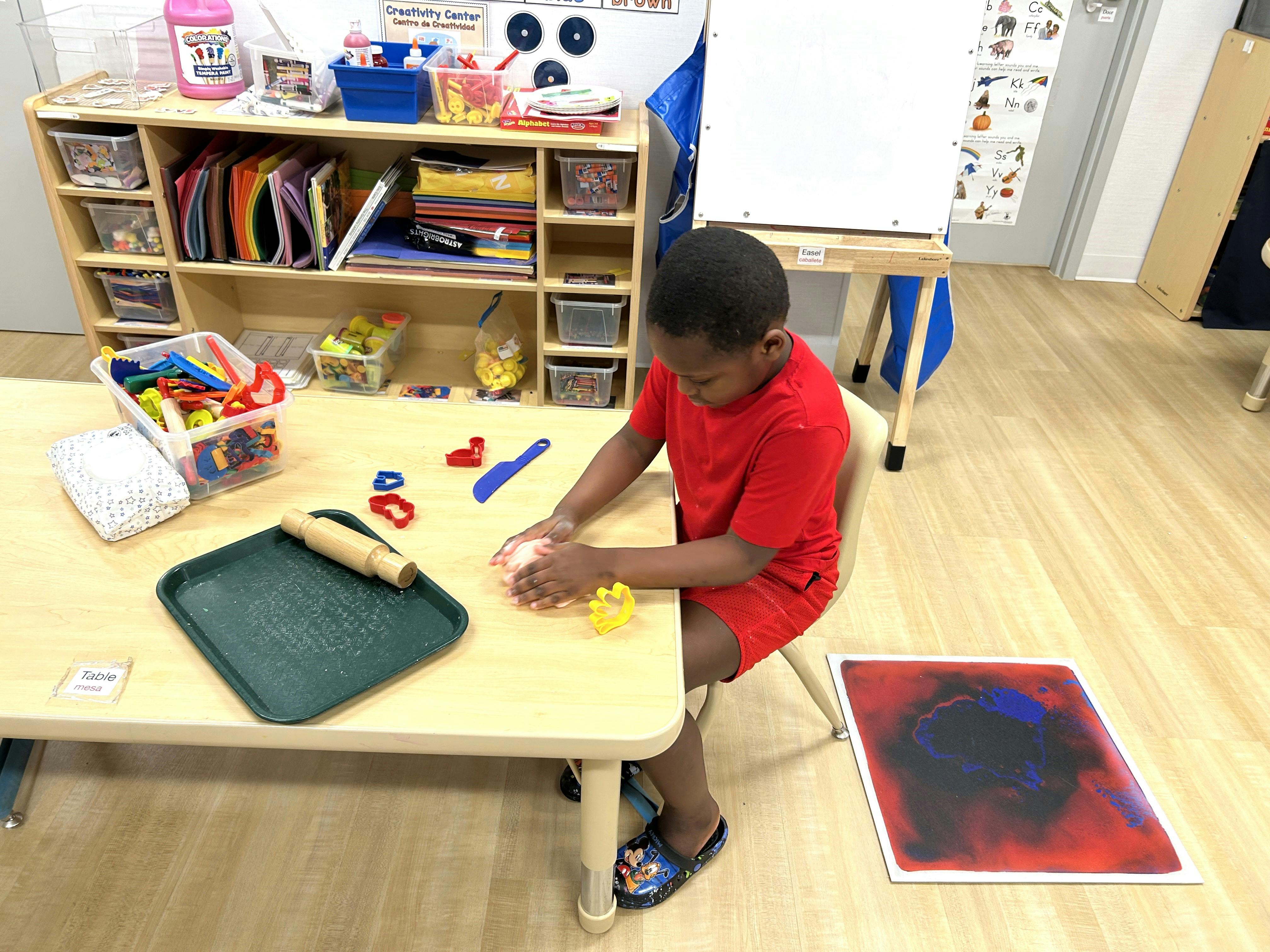 Child playing with modeling clay at a table