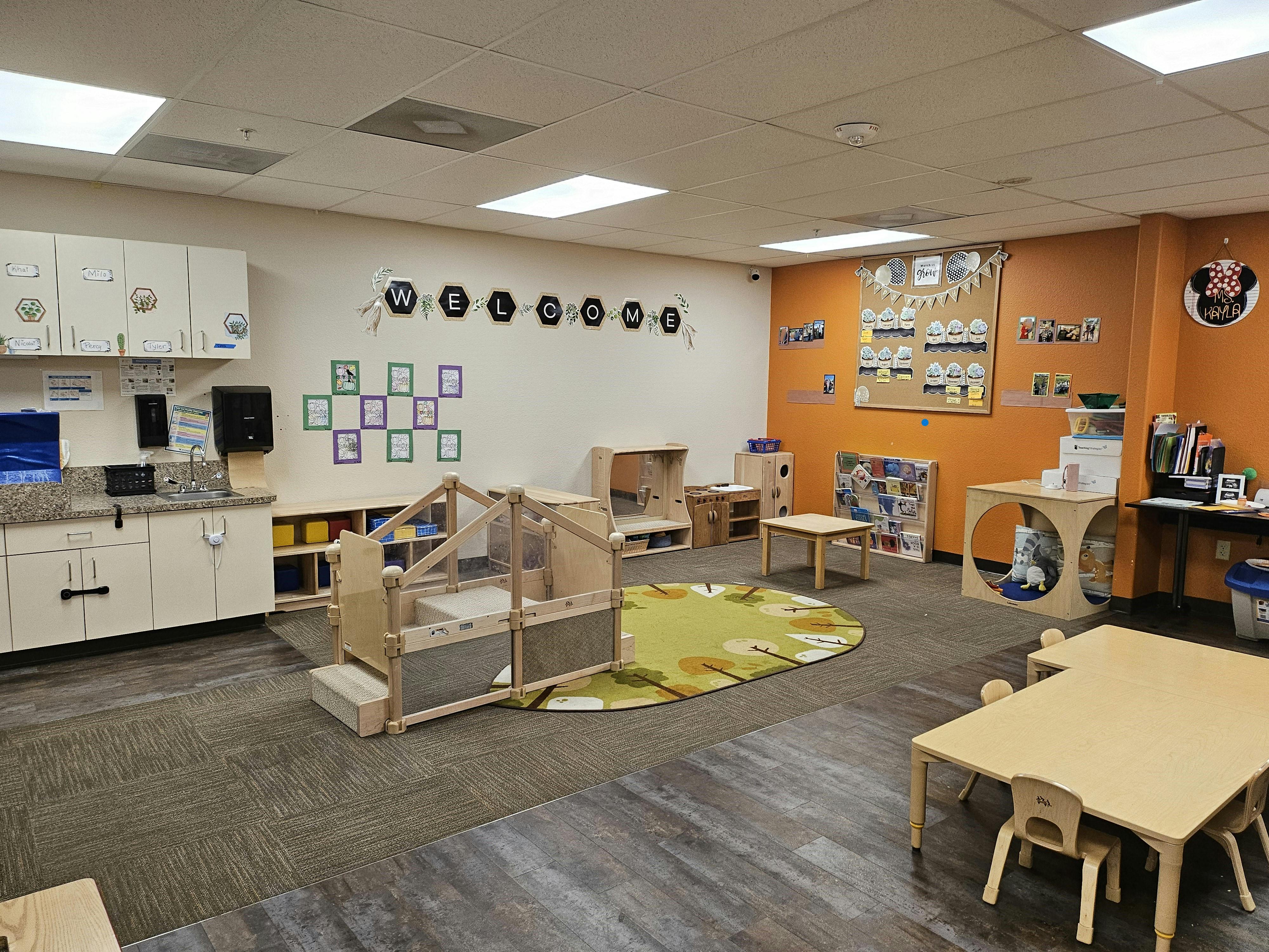 Empty classroom with play structures, tables, and a welcome sign