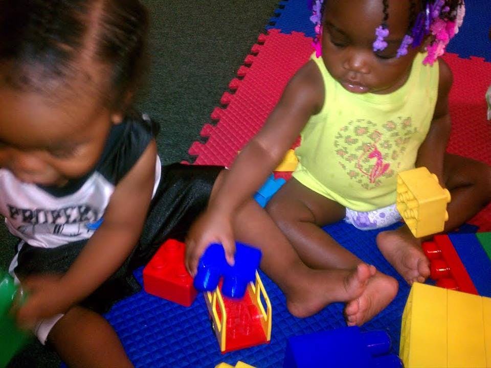 Two children playing with colorful building blocks on a mat