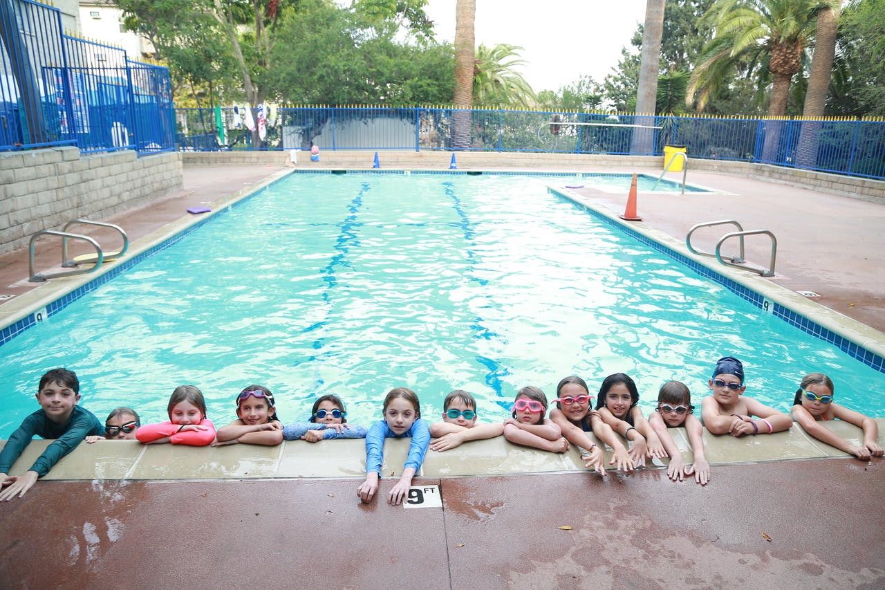 Children in a swimming pool with their arms on the edge