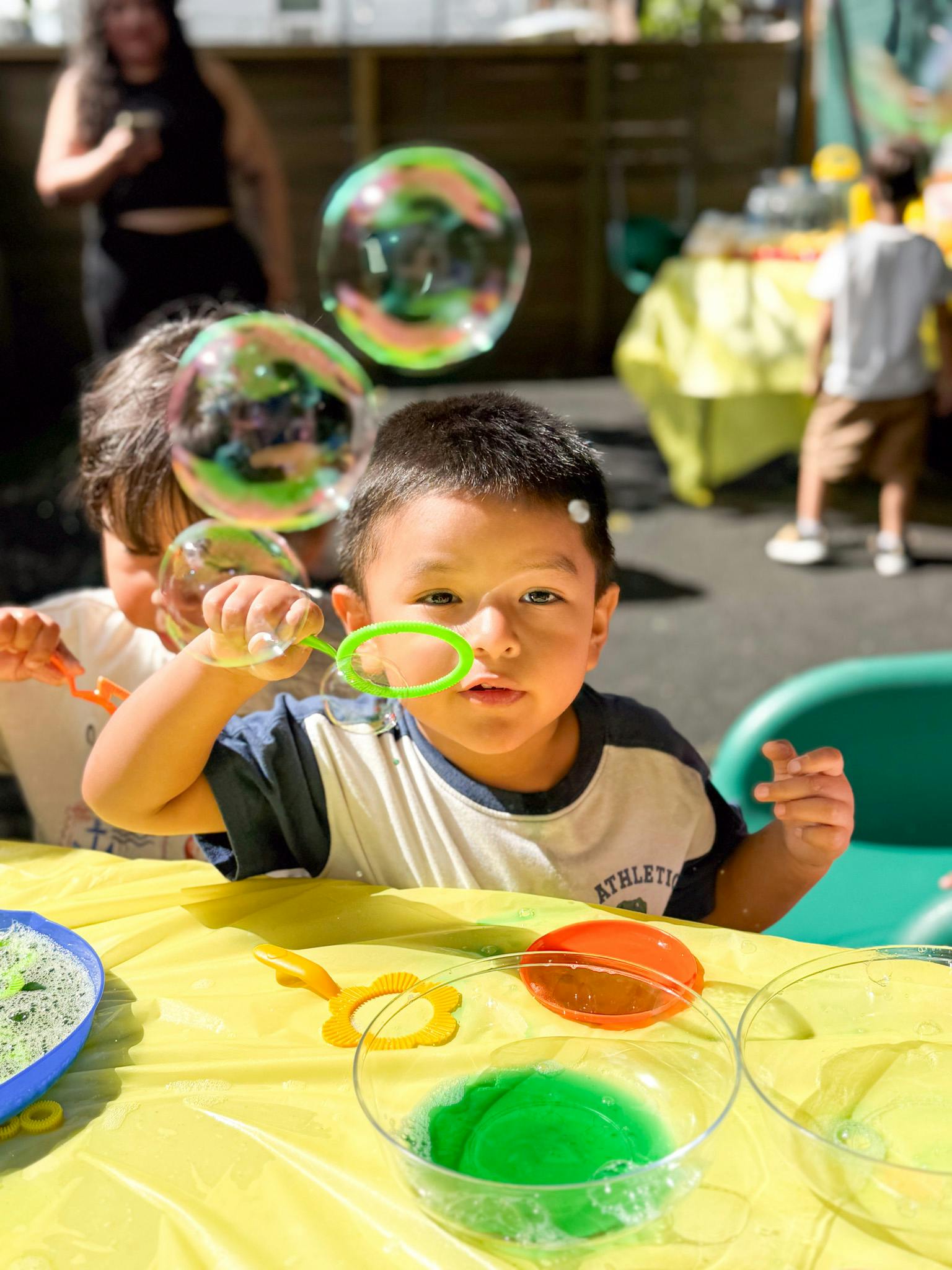 Child blowing bubbles at a table