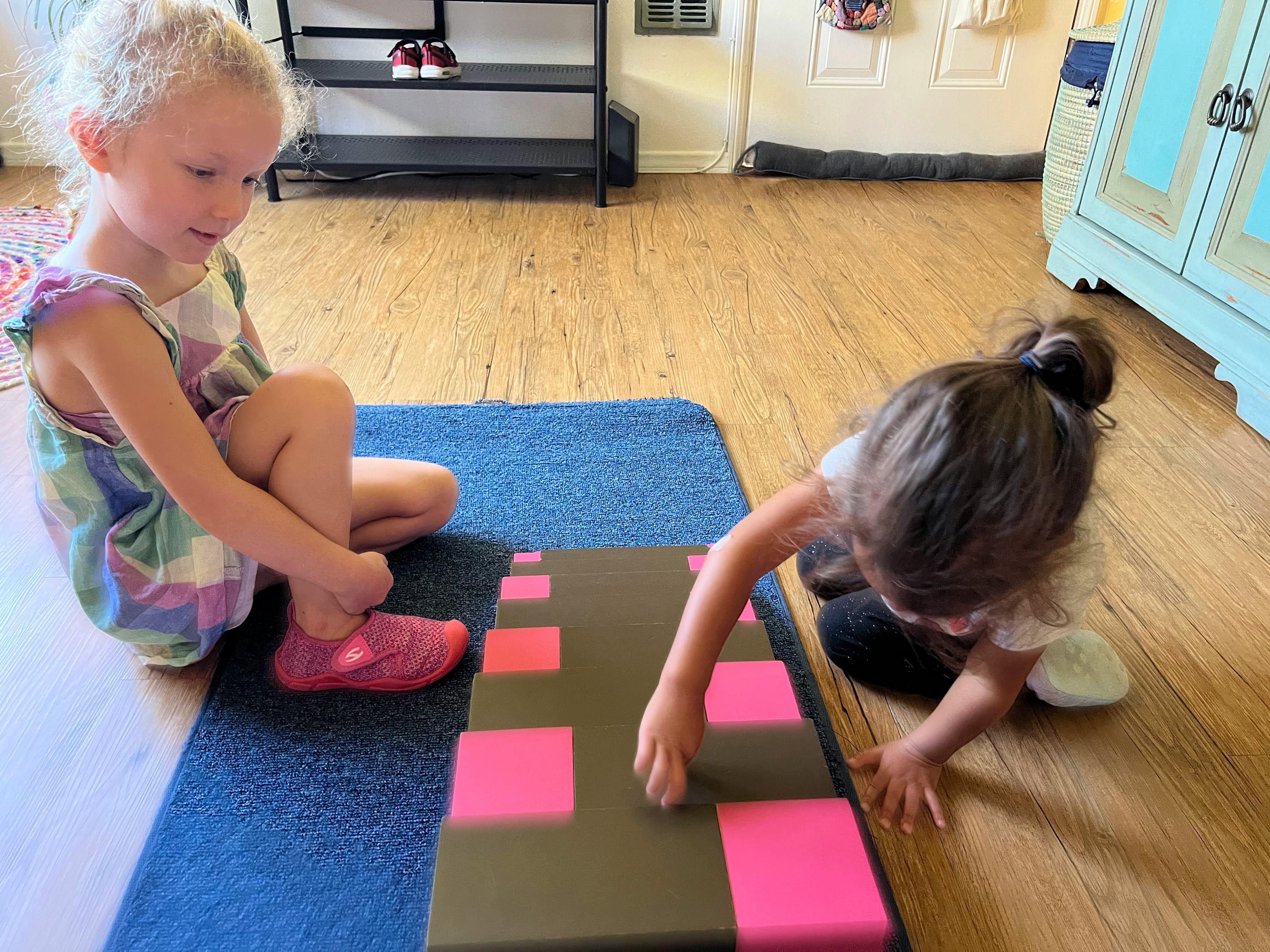 Two children playing with a board game on the floor