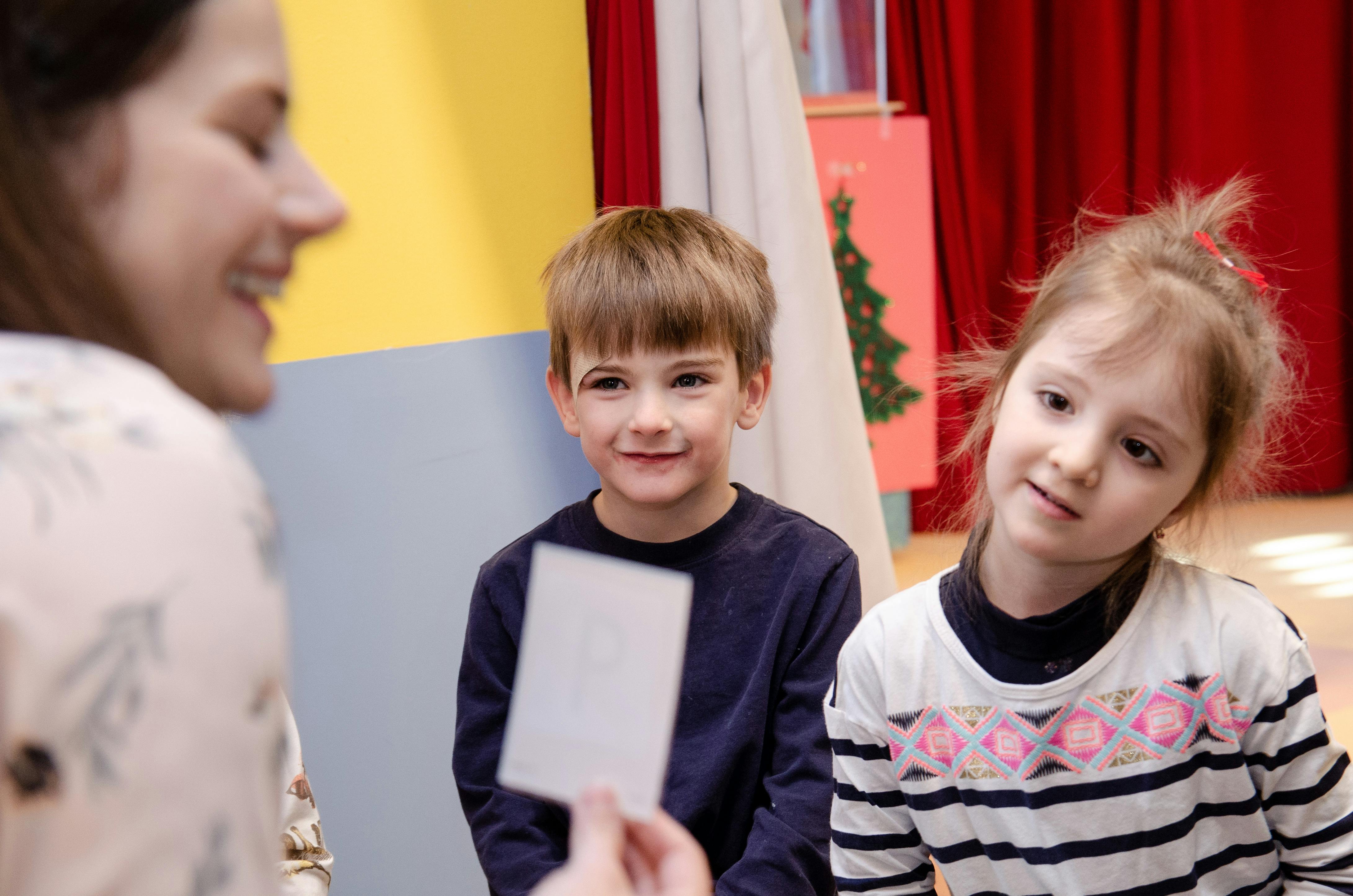 Person holding a card in front of two children