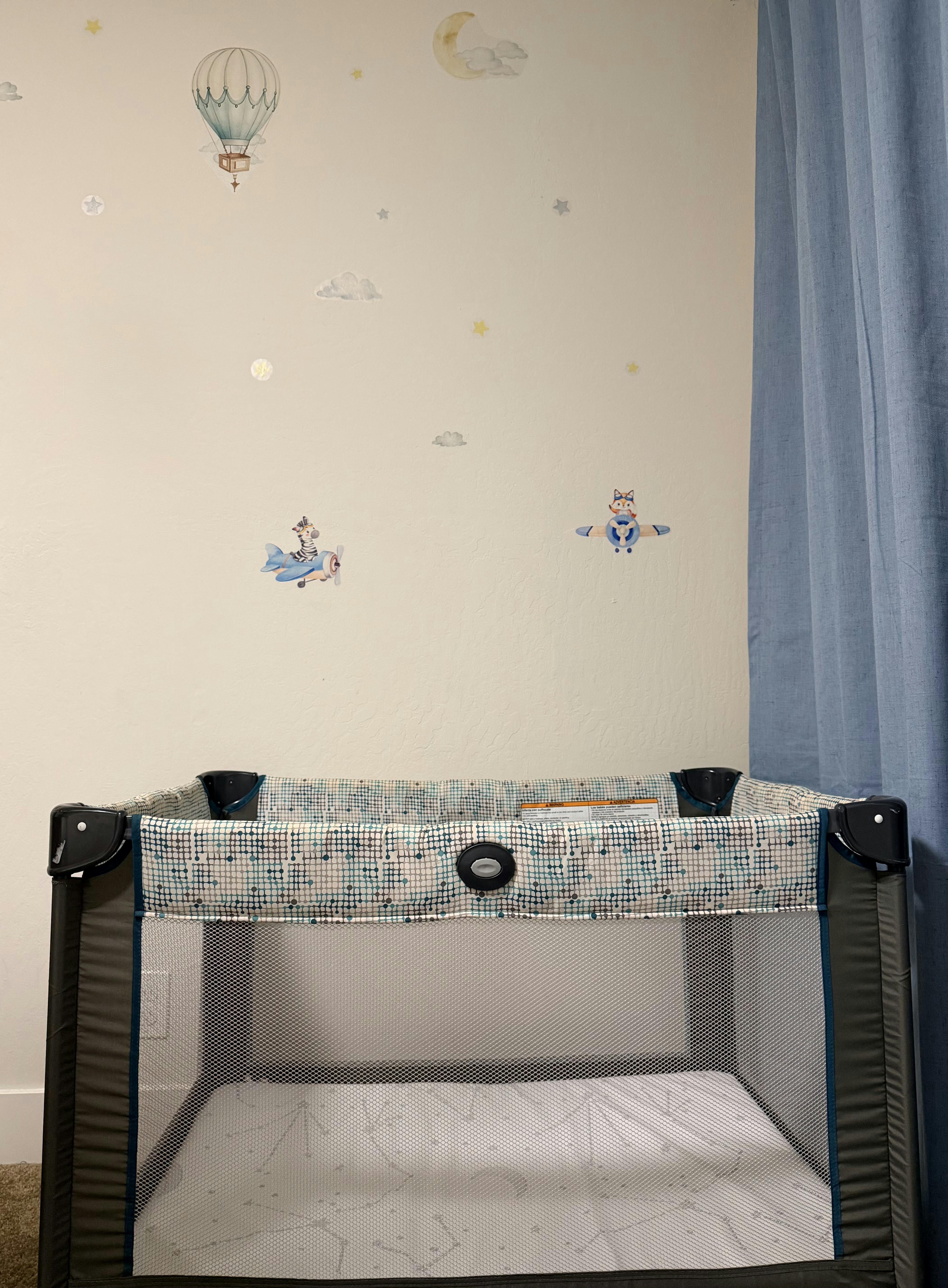 Playard in a nursery with hot air balloon and airplane wall decals
