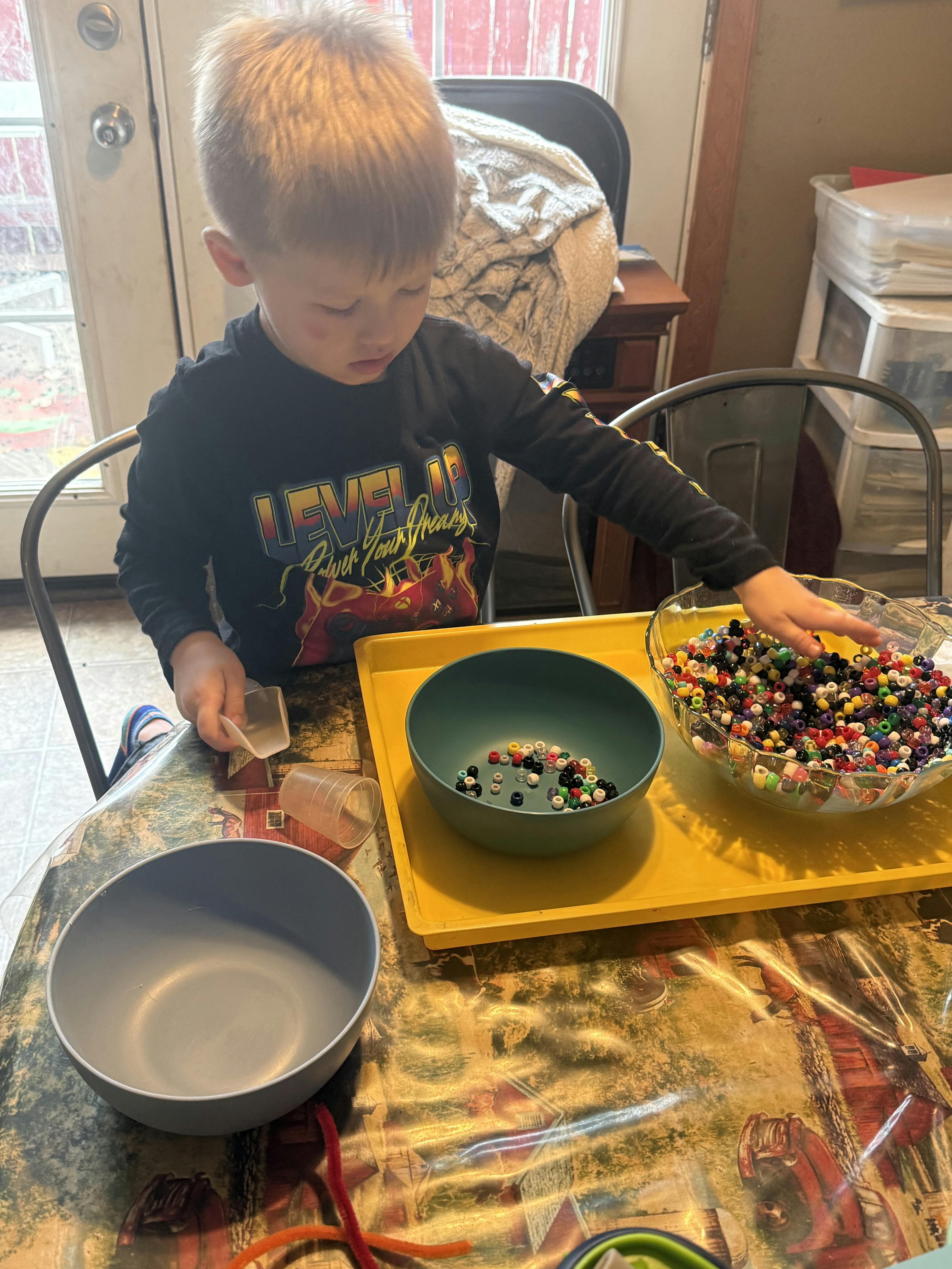 Child playing with colorful beads and bowls on a table