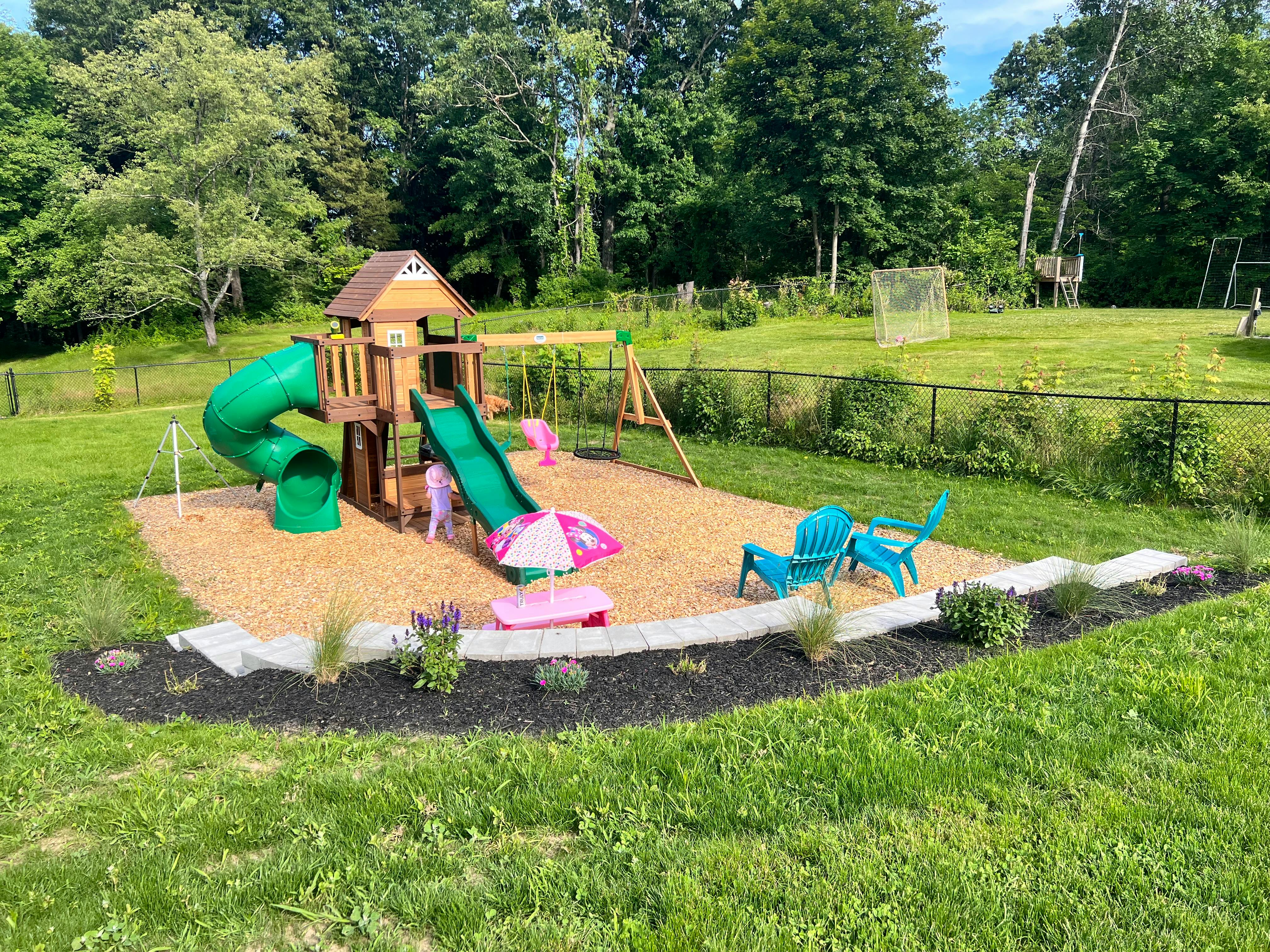 Outdoor playground with slides, swings, and a playhouse on wood chips