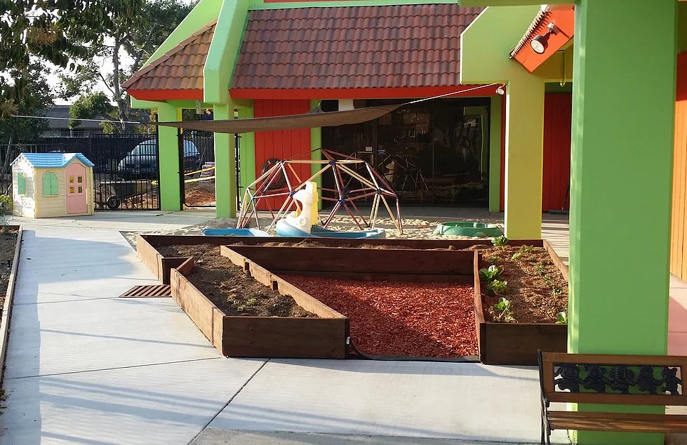 Outdoor play area with a colorful building, sandbox, and climbing structure