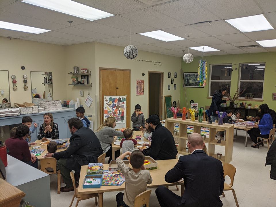 Adults and children sitting at tables in a classroom