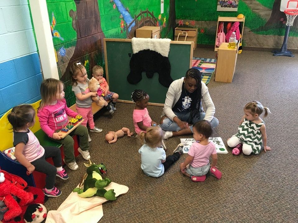 Adult and children sitting on the floor in a classroom