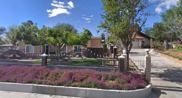 House with a fence and purple flowers in the foreground