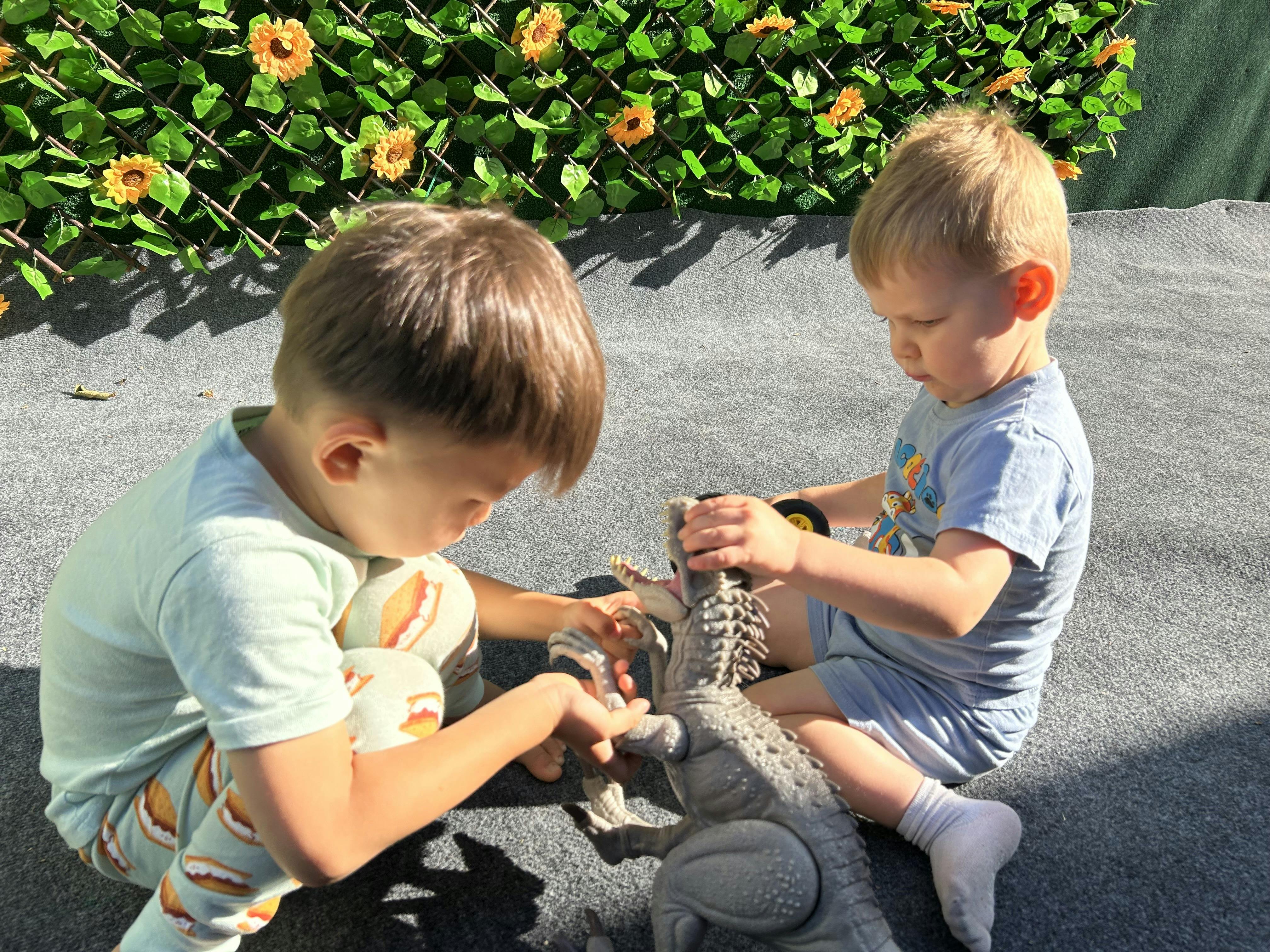 Two children playing with a toy dinosaur
