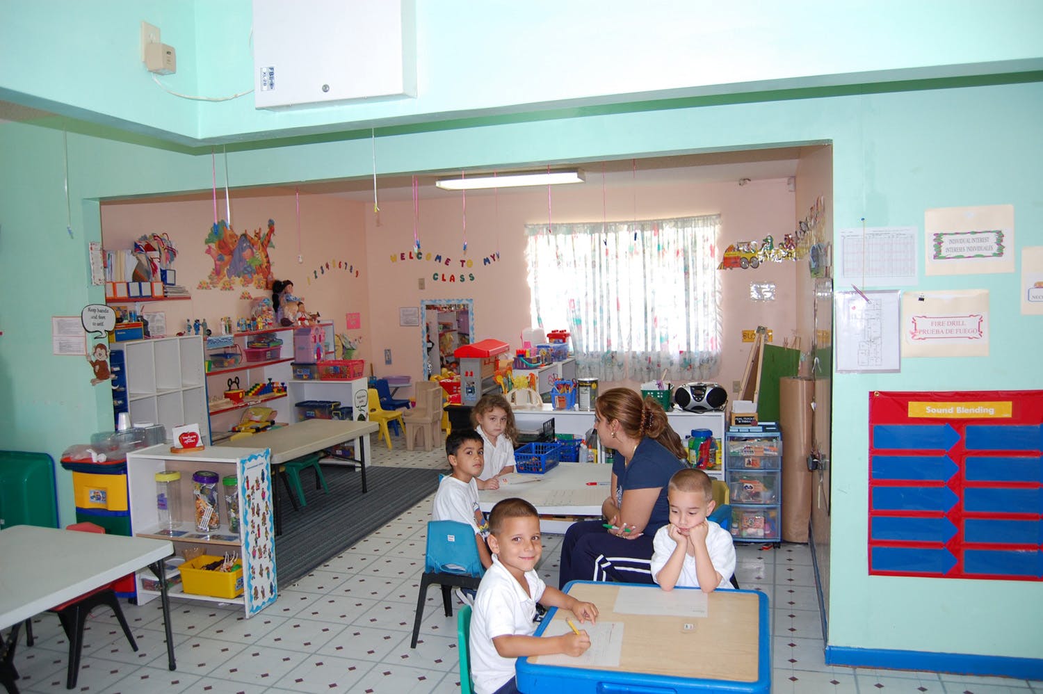 Adult and children sitting at tables in a classroom