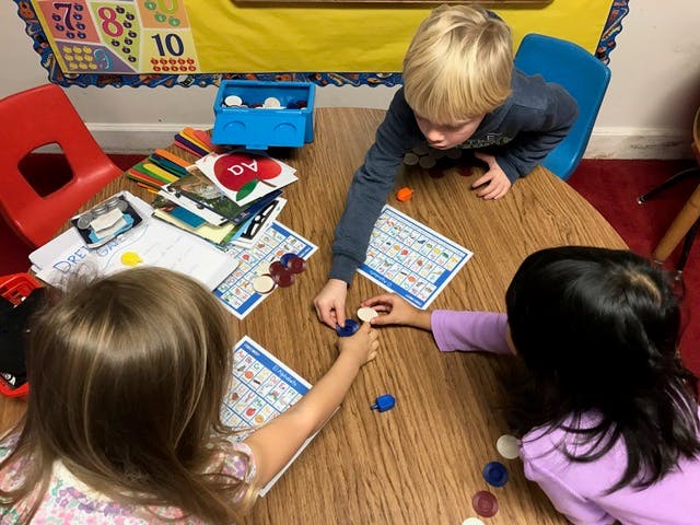 Three children playing with game pieces at a table